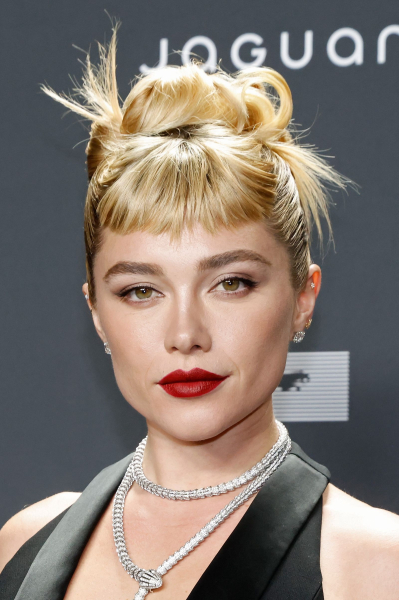 Florence Pugh wears short choppy bangs with an updo and red lip.
